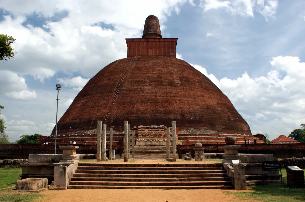 The huge red-brick dome of Jetavanaramaya in Anuradhapura rising behind a stepped stone entrance