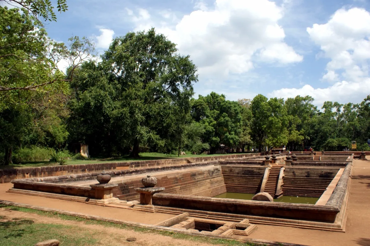 Two ancient stone-lined stepped ponds, the Kuttam Pokuna, among trees in Anuradhapura