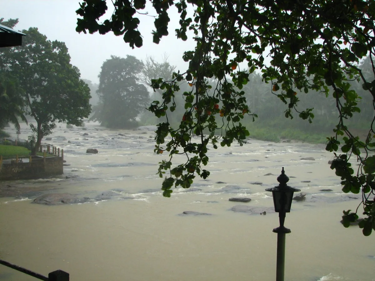 A brown, rain-swollen river rushes over rocks during a heavy afternoon rain in central Sri Lanka