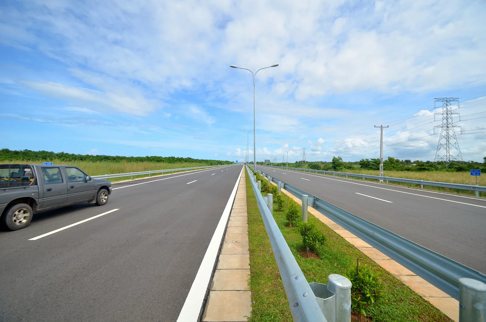 The Colombo-Katunayake Expressway running straight to the horizon, two empty lanes each way divided by a planted median under a blue sky