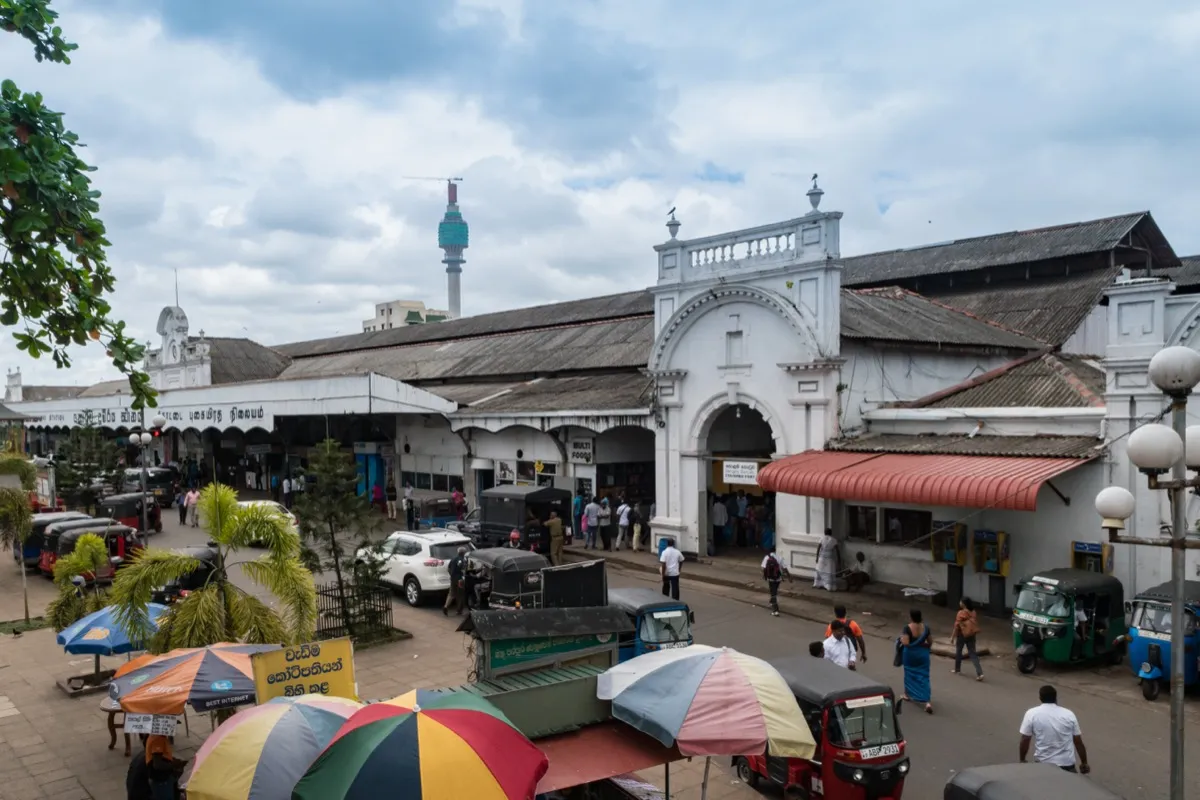 The white arched entrance of Colombo Fort railway station, with tuk-tuks parked outside