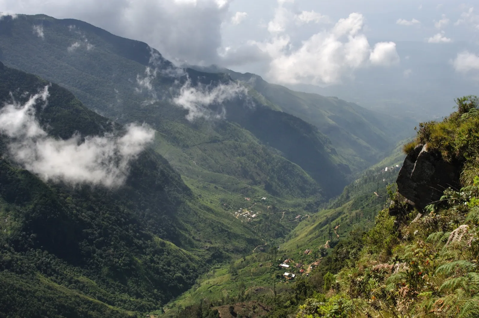 Looking down from the World's End cliff in Horton Plains into a green valley with villages far below and drifting cloud