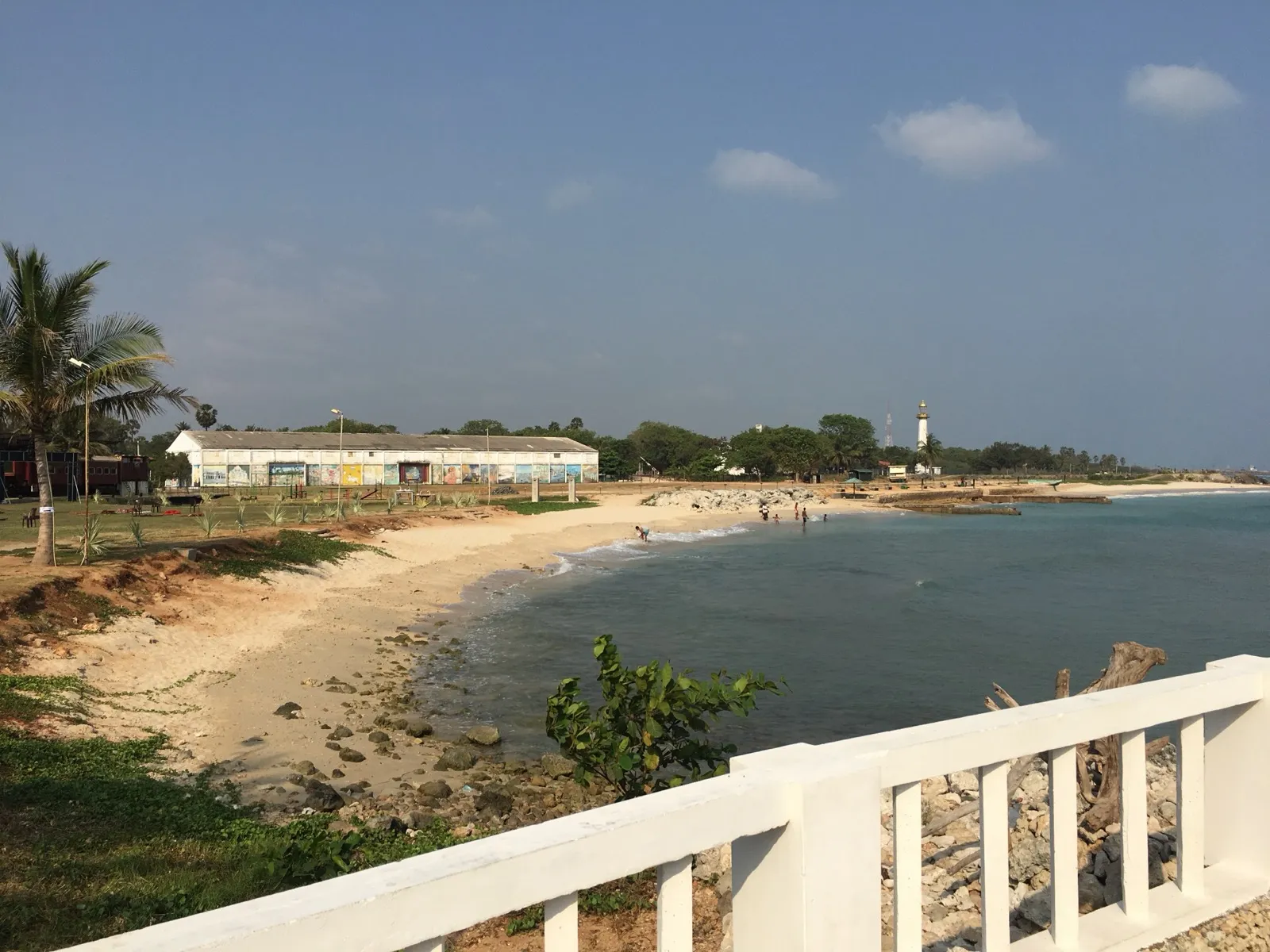 A curved sandy beach at Kankesanthurai in northern Sri Lanka, with a white lighthouse in the distance