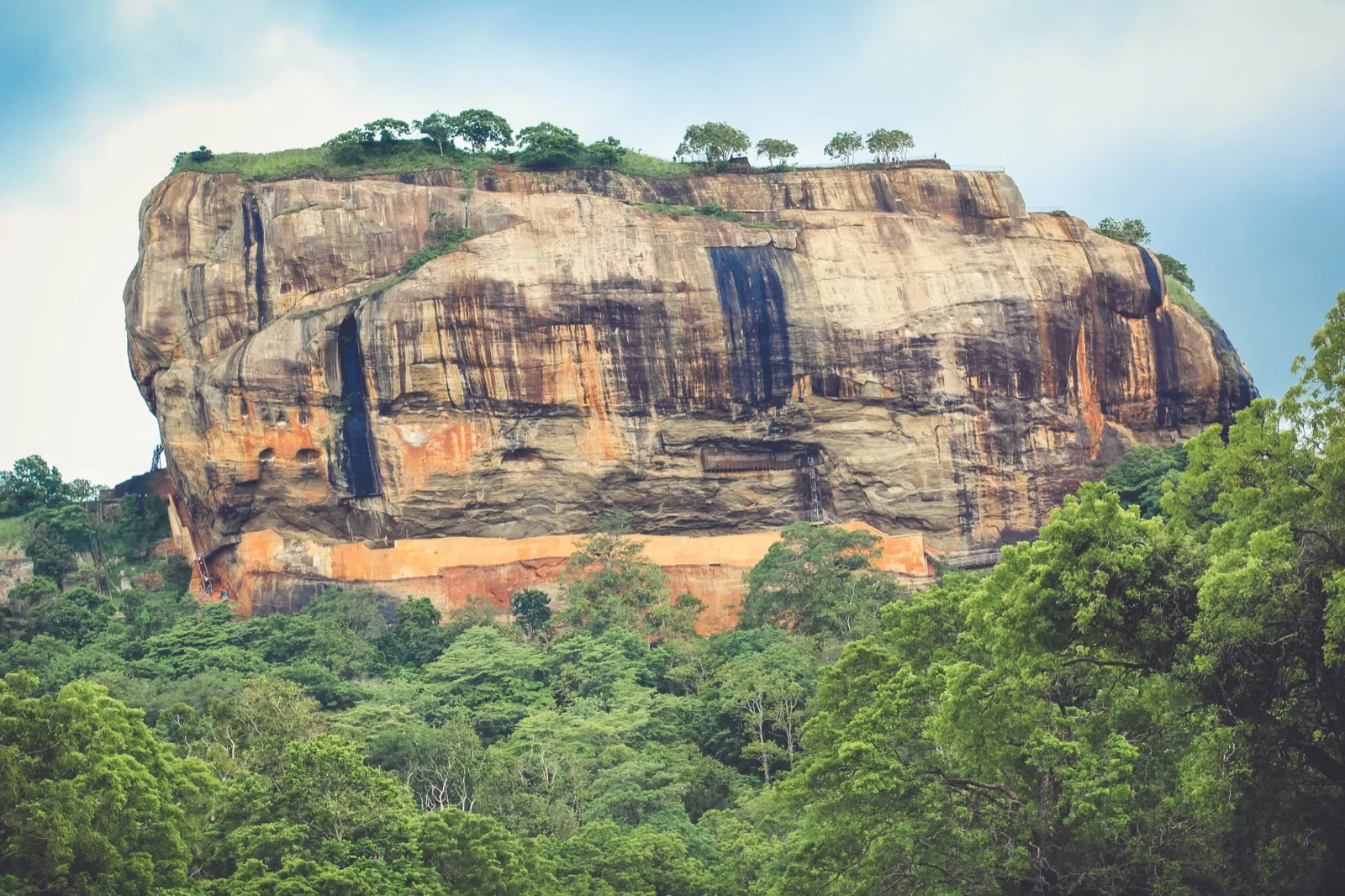 Sigiriya, a huge flat-topped rock rising above green forest in Sri Lanka