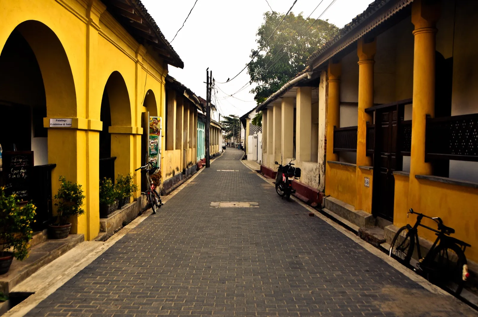 A quiet, empty lane inside Galle Fort, lined with yellow colonial houses and a parked bicycle