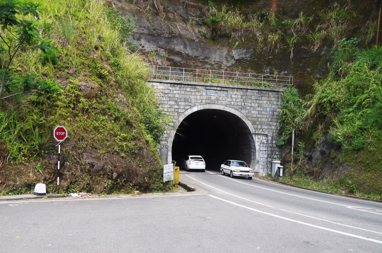 Two cars driving out of the stone-arched Ramboda Tunnel on the hill-country road between Kandy and Nuwara Eliya