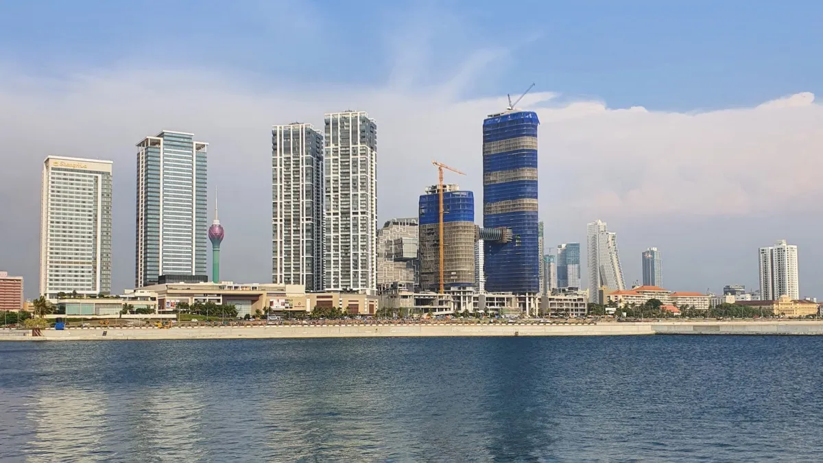 Colombo's waterfront skyline of high-rise towers and the Lotus Tower seen across calm water from Port City