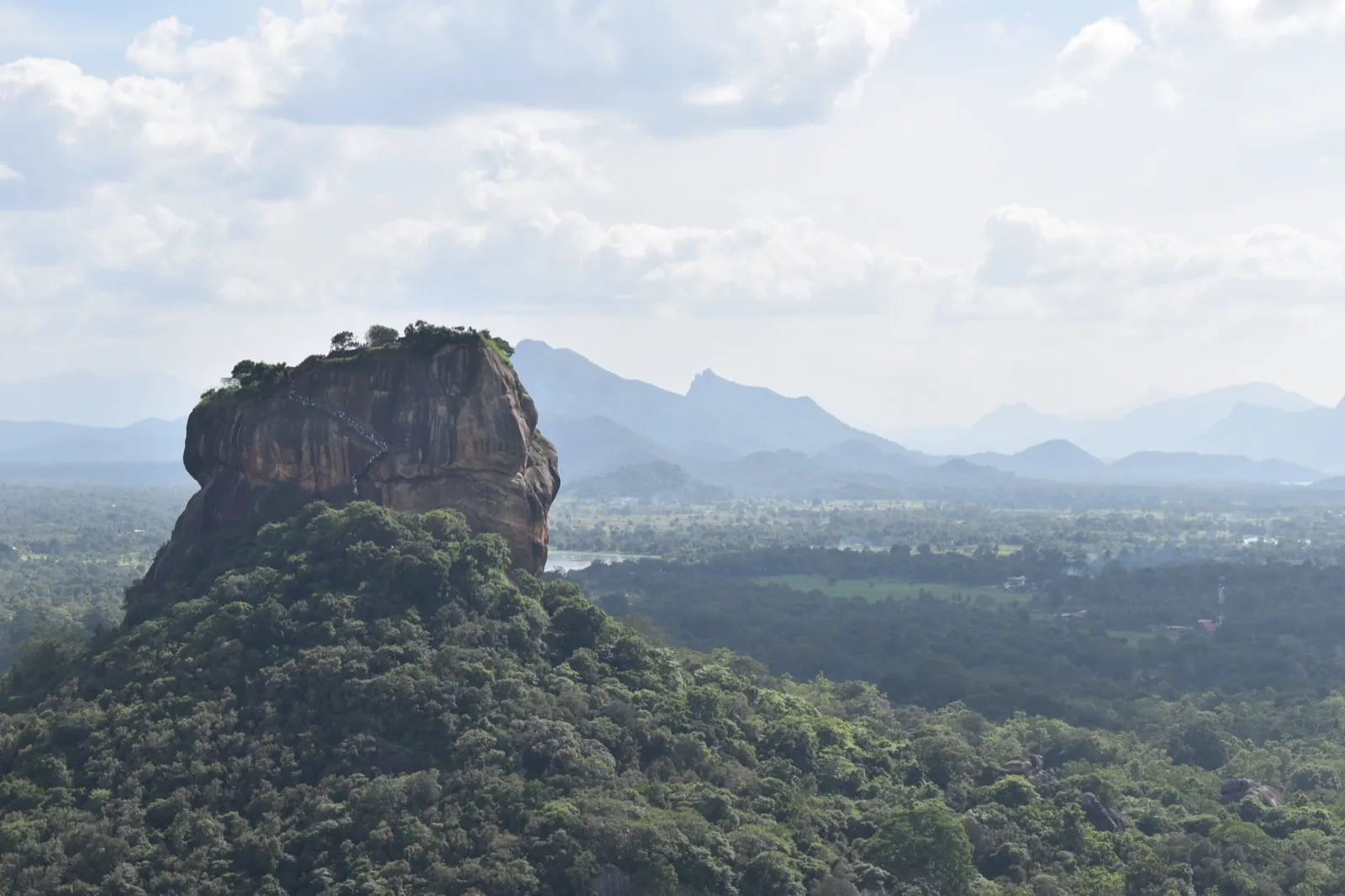 View from Pidurangala of Sigiriya rock standing above the forest, with hills on the horizon