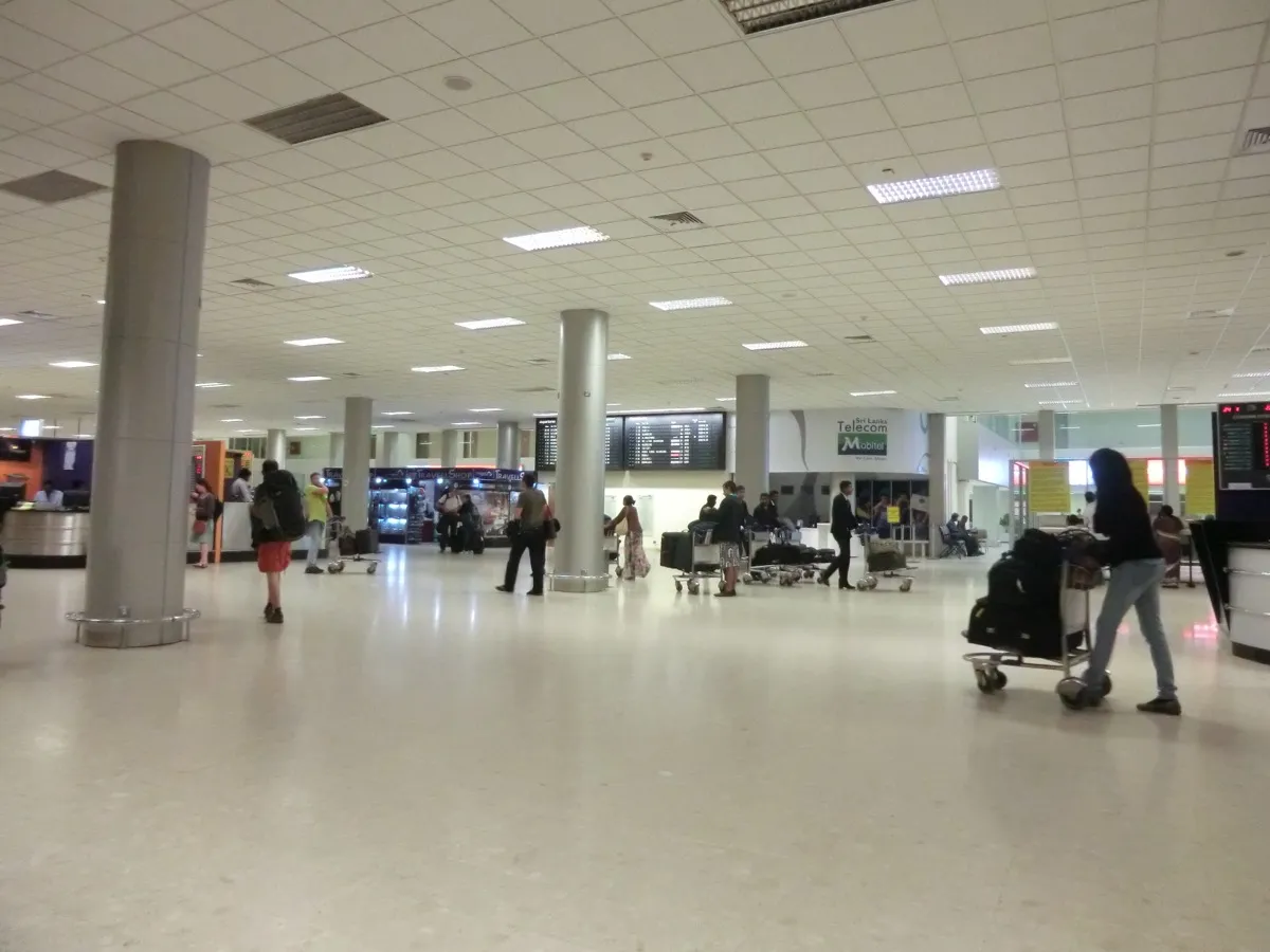 The arrivals hall at Colombo airport, with a mobile operator counter and travellers pushing luggage trolleys