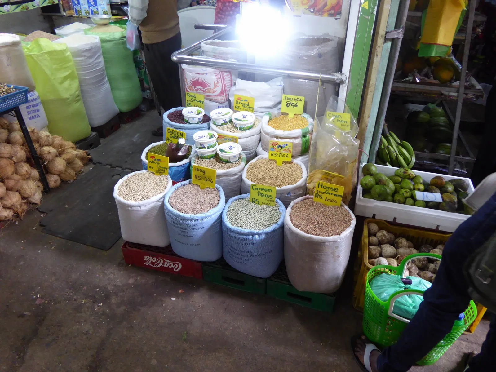 Open sacks of lentils, peas and beans at a market stall, each with a yellow price card in rupees