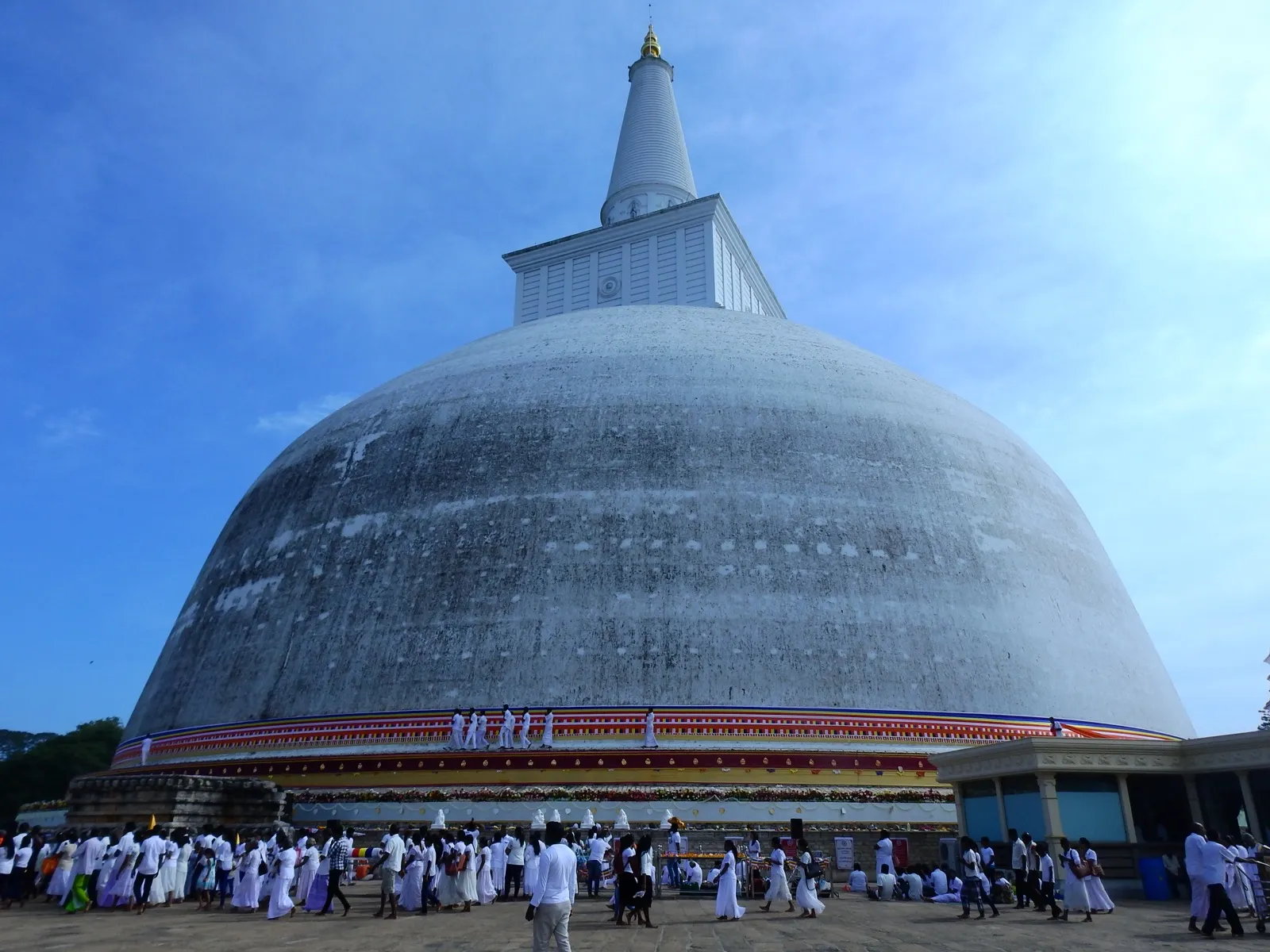 Pilgrims dressed in white walk barefoot around the great white Ruwanwelisaya dagoba in Anuradhapura