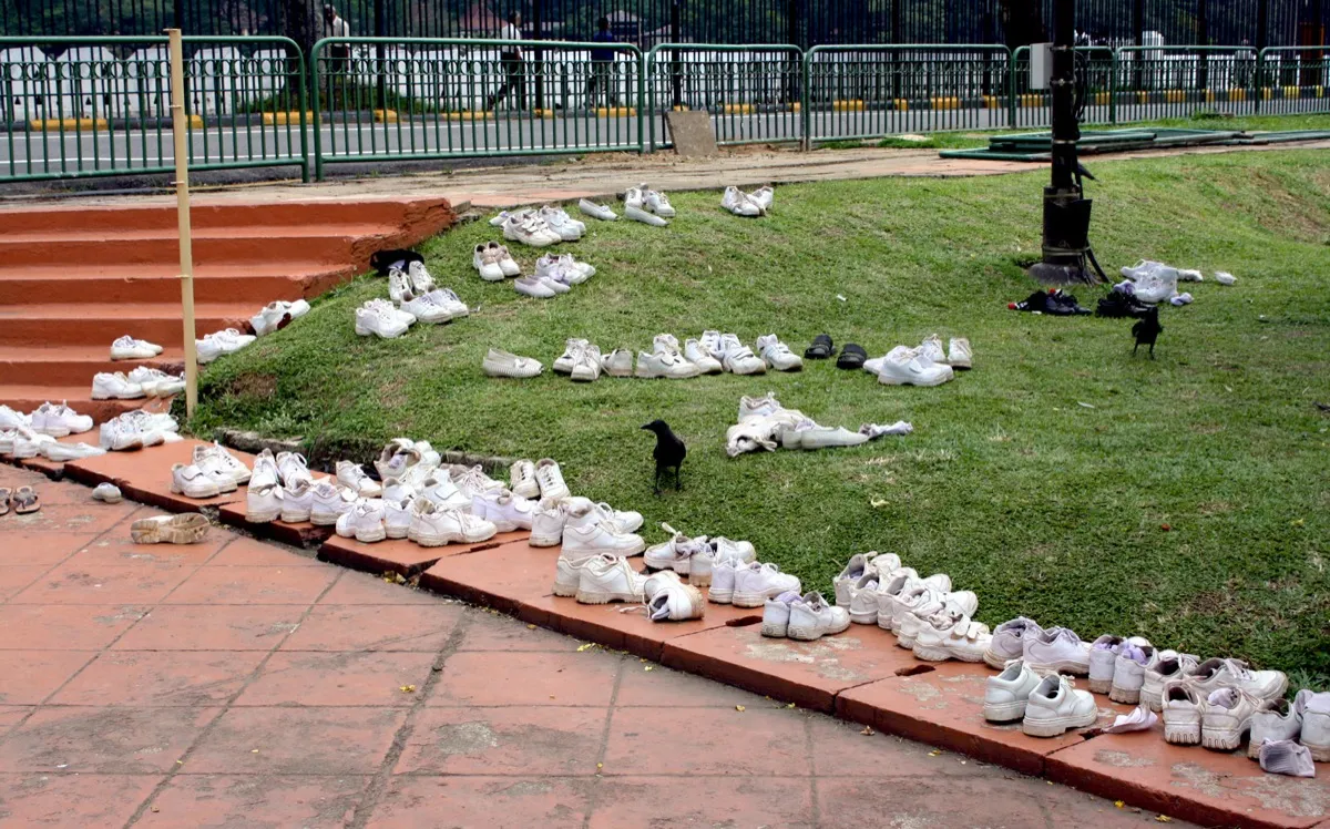 Rows of white shoes and sandals left on the grass outside a temple in Kandy