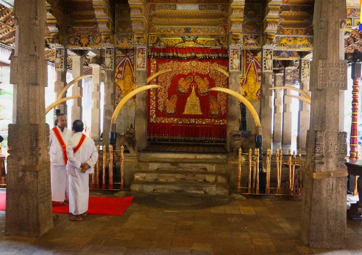 The relic chamber shrine at the Temple of the Tooth, framed by elephant tusks, with two officials in white standing nearby