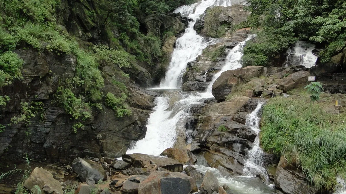 Ravana Falls near Ella, white water dropping in several cascades over dark rock ledges between green banks